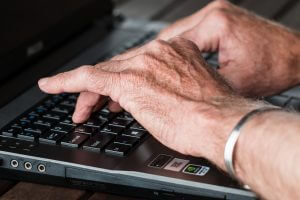 oude handen typen op toetsenbord laptop