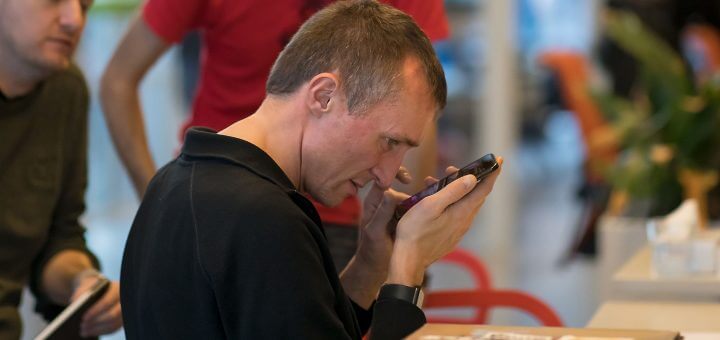 Man houdt telefoon dichtbij de ogen. Toegankelijkheid, accessibility