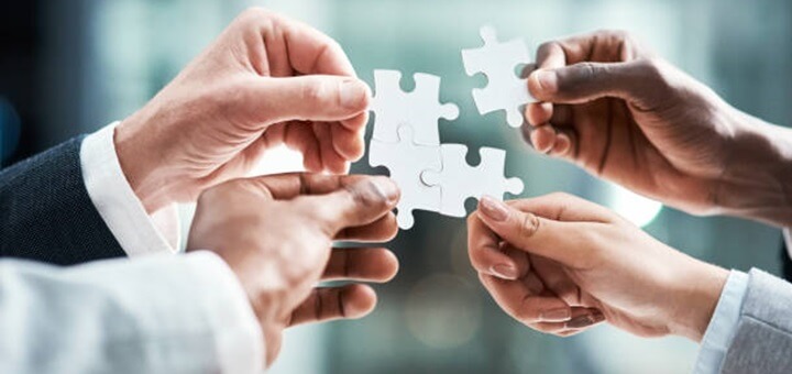 Closeup shot of a group of unrecognizable businesspeople holding puzzle pieces together