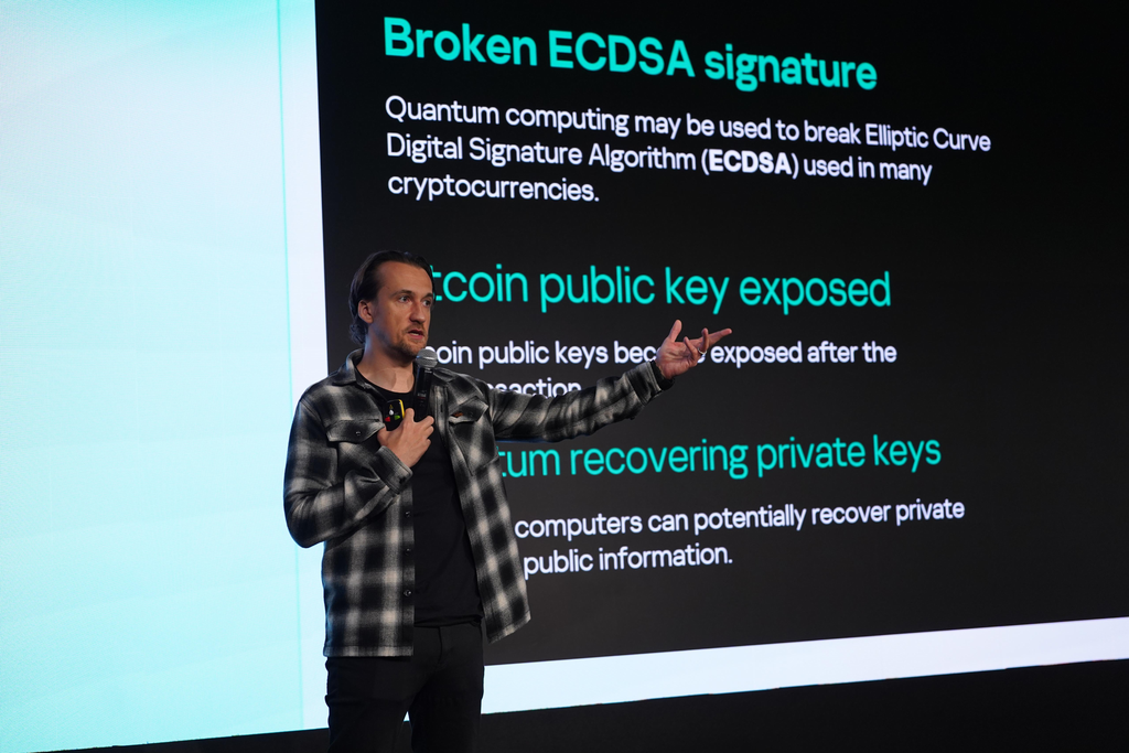 SergeyLozhkin 3 Een spreker staat op het podium en presenteert dia's over de risico's van kwantumcomputing voor ECDSA-handtekeningen en de beveiliging van cryptocurrency.