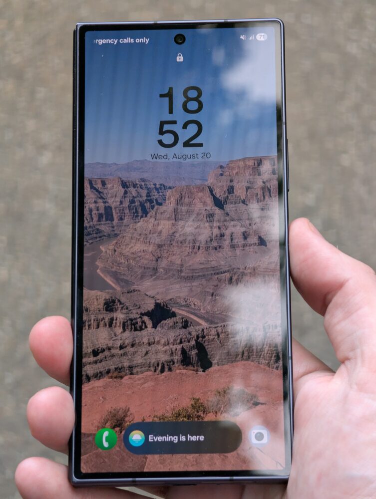 Een hand houdt een Samsung Galaxy Z Fold 7 vast waarop de tijd 18:52 en de datum 20 augustus worden weergegeven, met een achtergrond van een canyonlandschap en een melding "Evening is here" op het vergrendelscherm.