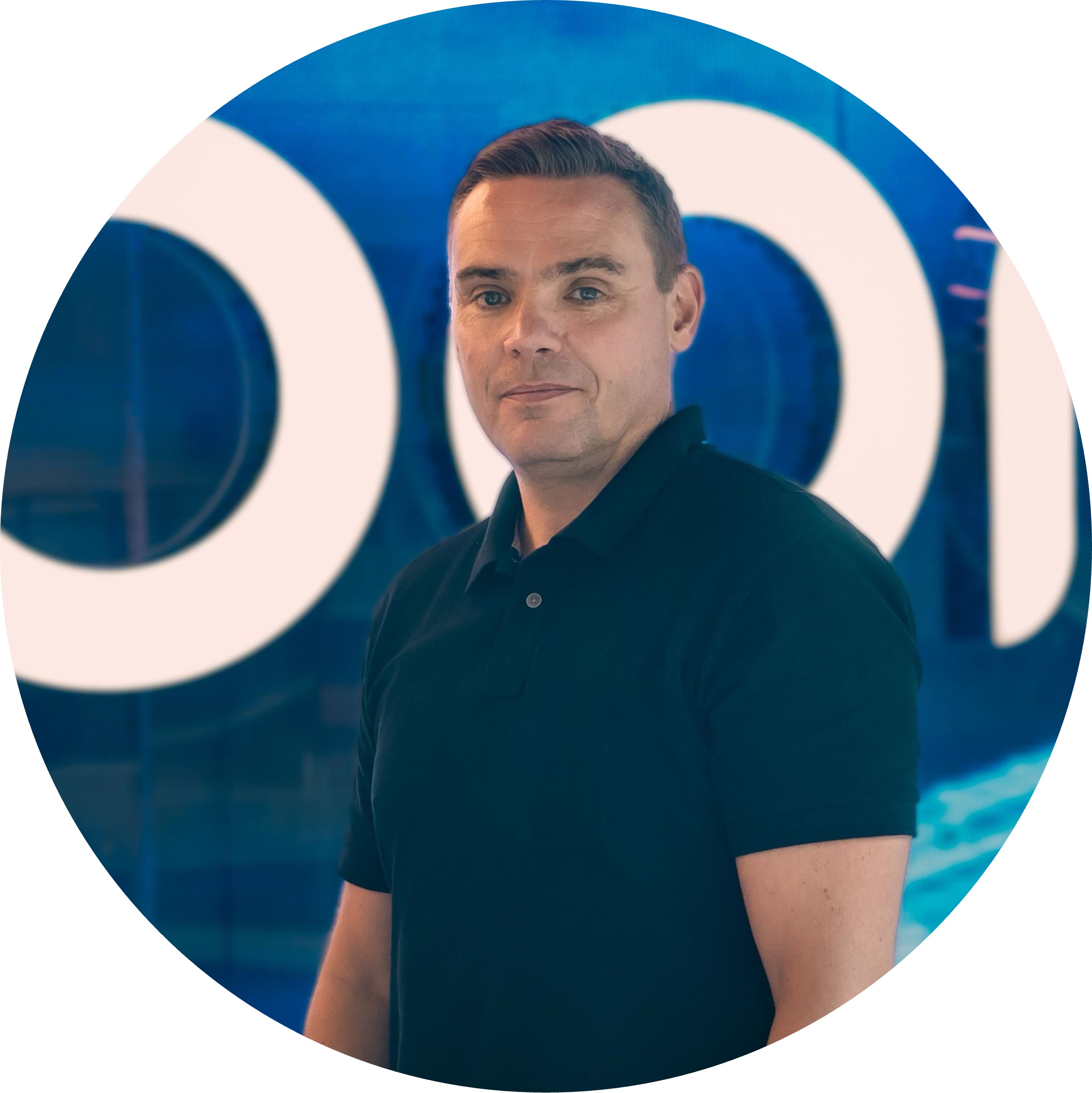 Steve Rafferty Een man in een zwart poloshirt staat voor een blauwe achtergrond met grote witte letters en presenteert inzichten over de Zoom AI-platform strategie.