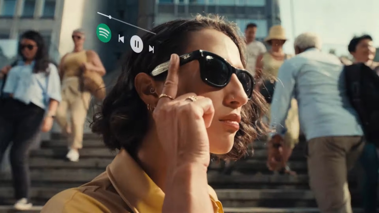 Een persoon met een slimme zonnebril raakt het montuur aan, met daarnaast een Spotify-muziekinterface en pauzeknop in een drukke stedelijke buitenomgeving, wat doet denken aan de naadloze technische integratie van Apple Vision Pro.