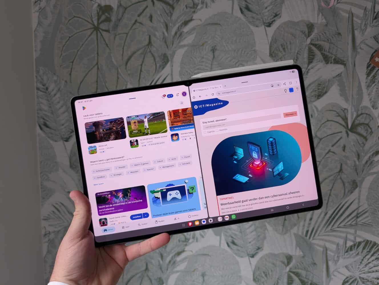 Een hand houdt een uitklapbare Samsung Galaxy Tab S11 Ultra tablet open en toont twee apps naast elkaar: links een gameswinkel en rechts een website.