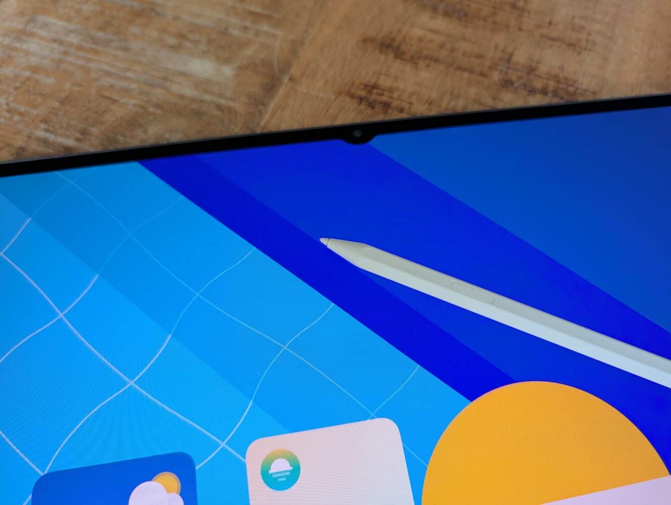 Een close-up van het scherm van een Samsung Galaxy Tab S11 Ultra met kleurrijke app-pictogrammen en een witte stylus die op het scherm rust, op een houten oppervlak.