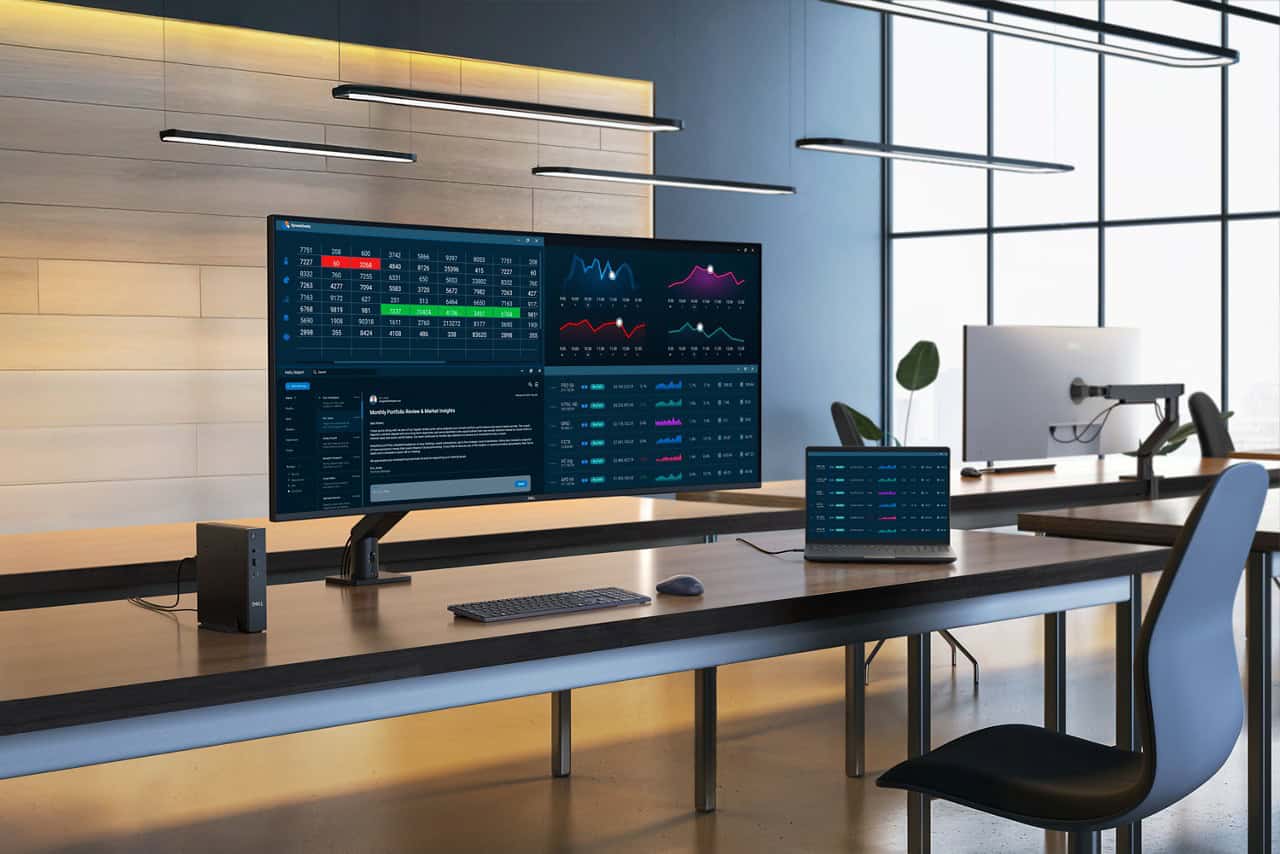 Grote Dell monitor en laptop op een modern bureau die gegevens en grafieken weergeven, met een minimalistisch decor en grote ramen op de achtergrond.