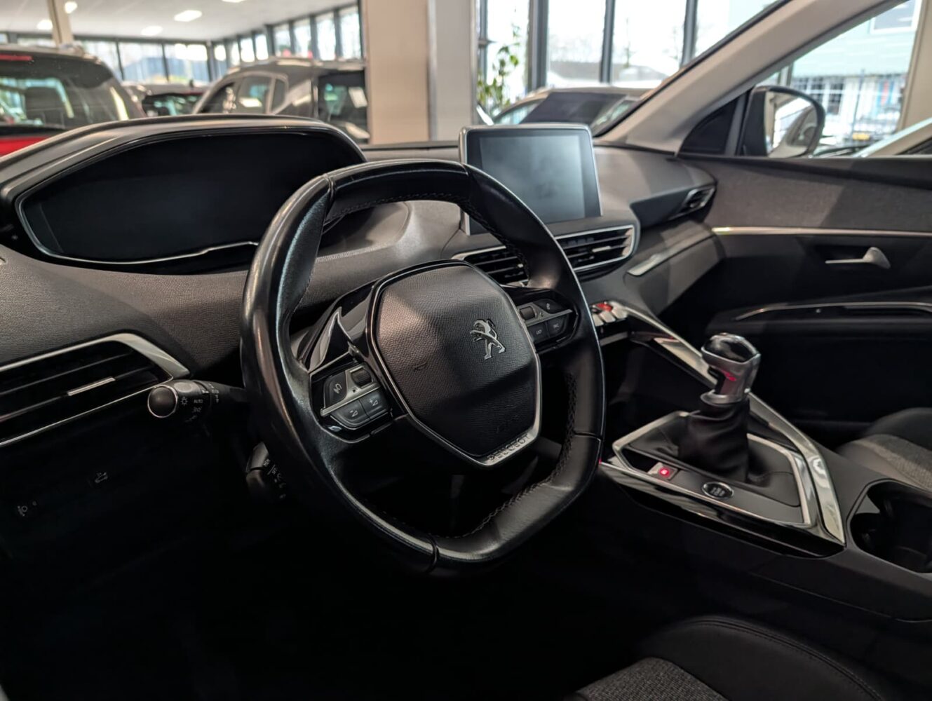 Interieur van een Peugeot-auto met het stuur, dashboard, centrale touchscreen en versnellingspook, allemaal vastgelegd in een dealer met indrukwekkende helderheid op een Google Pixel 10 Pro.
