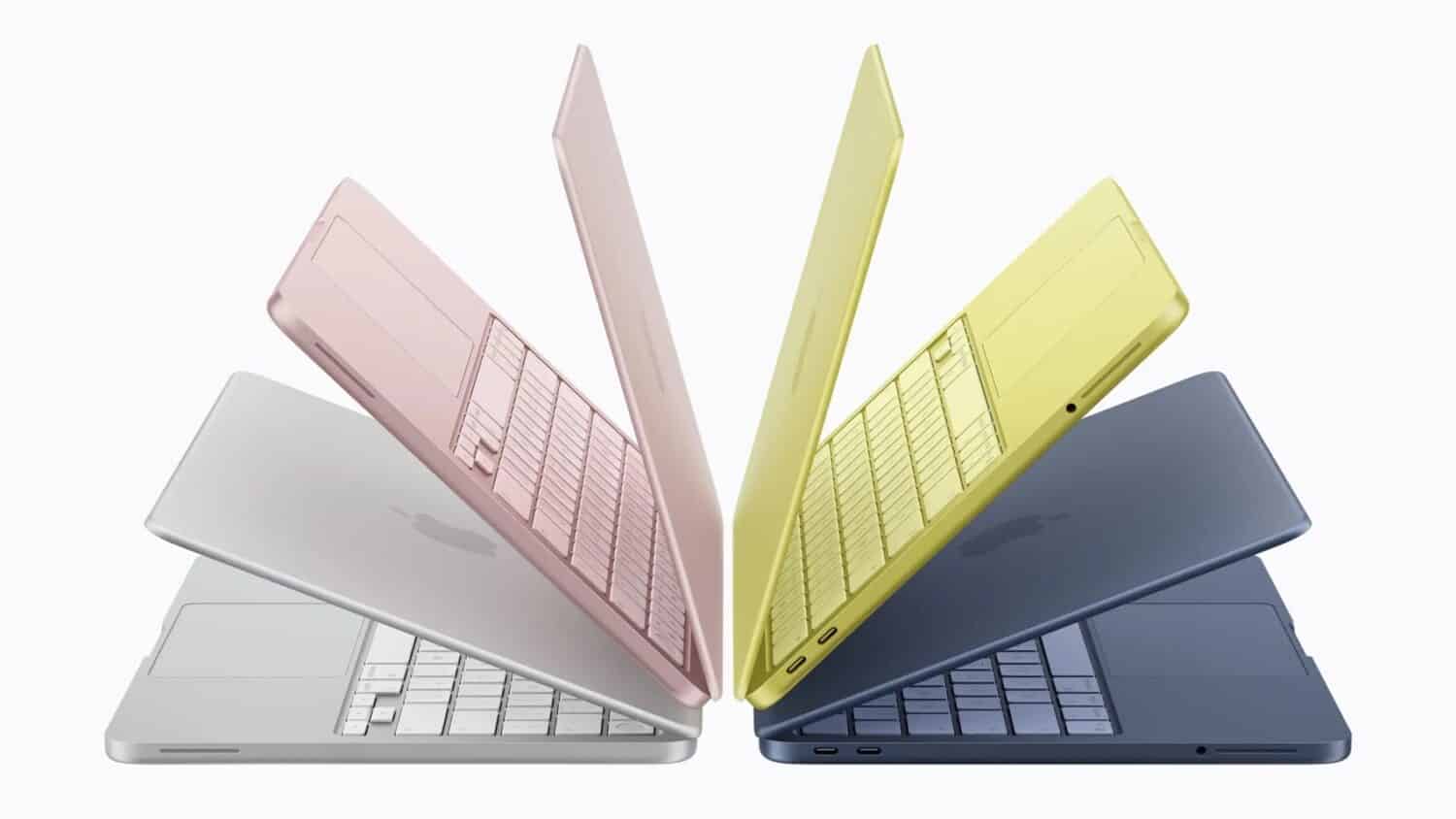 Vier gedeeltelijk open Apple laptops in zilver, roze, geel en blauw staan in een symmetrisch, waaiervormig patroon op een effen achtergrond.