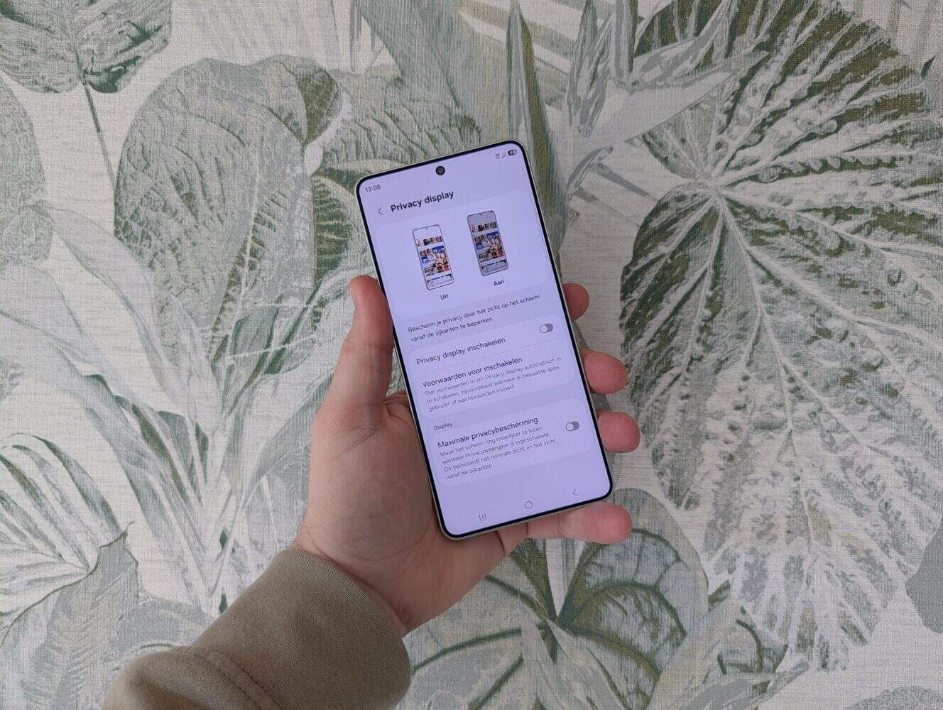 Een hand die een smartphone vasthoudt met de privacy-instellingen op de display, met een achtergrond van bladeren - vergelijkbaar met de functies die naar voren kwamen in de Samsung Galaxy S26 Ultra review.