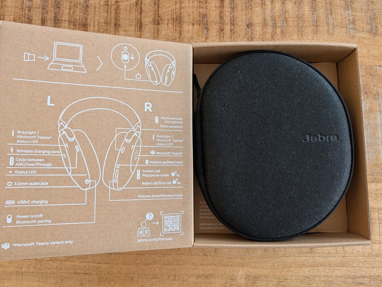 Een open Jabra Evolve3 headset-doos met installatie-instructies aan de linkerkant en een zwart Jabra draagtasje aan de rechterkant, allemaal geplaatst op een houten oppervlak - perfect voor een gedetailleerde Jabra Evolve3 review.